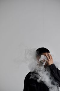 Man amidst smoke against white background