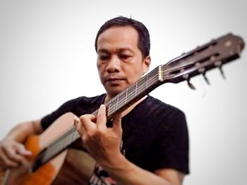 Man playing guitar against white background