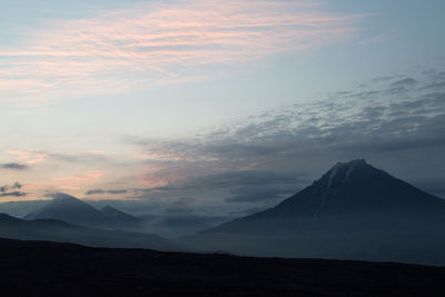 Scenic view of mountain against cloudy sky during sunset