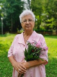 Portrait of woman with arms raised standing against plants