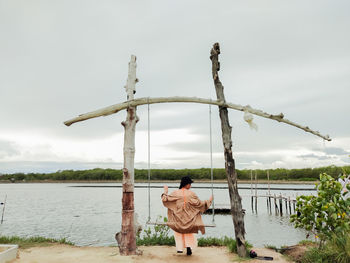 A woman sat on the swing by the sea