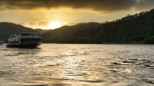 Boat sailing in sea against sky during sunset