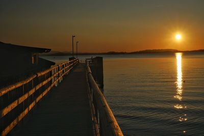 Pier over sea against sky during sunset