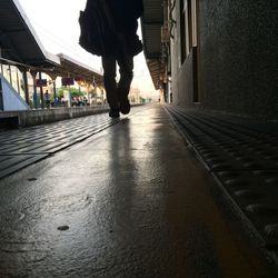 Low section of man walking on wet street