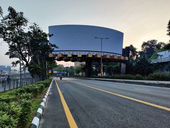 Road by trees against sky in city