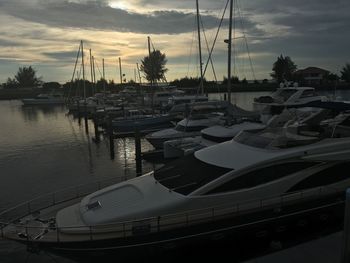 Boats sailing in harbor at sunset