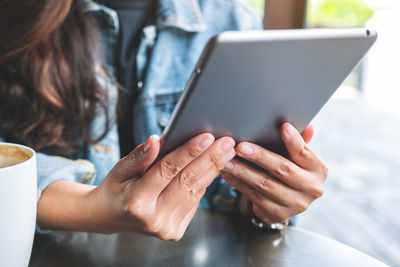 Midsection of woman digital tablet on table