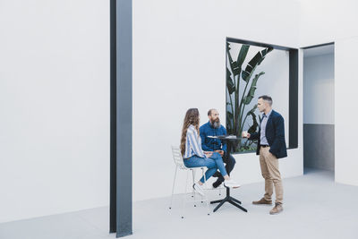 Group of busy coworkers gathering at table and working together on project in modern workspace