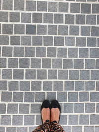 Low section of woman standing on pattern footpath