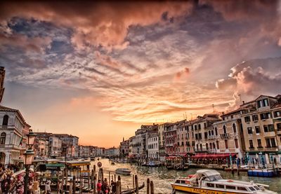 Boats at harbor against cloudy sky
