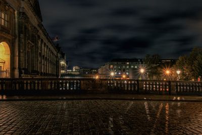 Illuminated buildings by river against sky at night