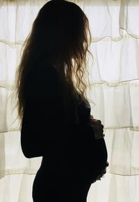 Side view of silhouette pregnant woman standing at home