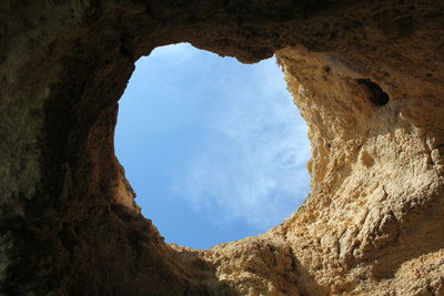 Low angle view of rocky wall against sky