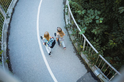 High angle view of friends walking on bridge by trees