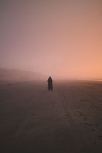 Silhouette man in desert against sky during sunset