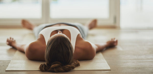 Woman lying on exercise mat at gym