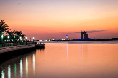 Reflection of illuminated building in sea at sunset