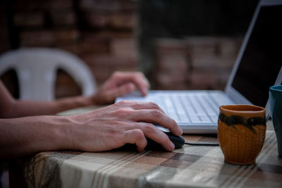 Close-up view of male hands working on laptop outside the house. a businessman works on  notebook 