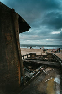 Abandoned metallic structure on beach against sky