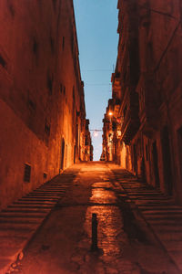 Narrow alley amidst buildings at night