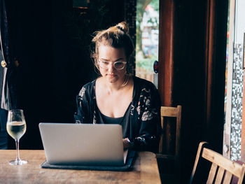 Young woman using laptop in bar