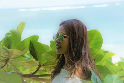 Portrait of young woman looking at plant