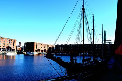 Boats in river against clear blue sky