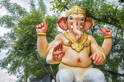 Low angle view of ganesha statue against trees