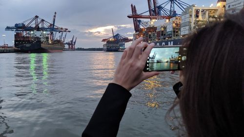 Man photographing at harbor against sky