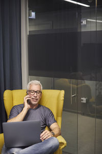 Businessman talking on phone and using laptop