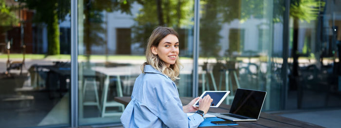 Portrait of young woman using laptop at cafe