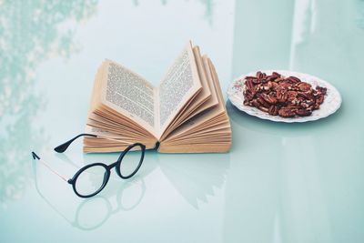 Open book and eyeglasses with food in plate on table