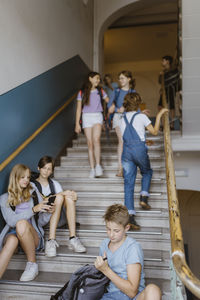 Multiracial male and female students on staircase during recess at school