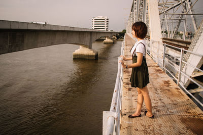 Side view of woman standing on bridge