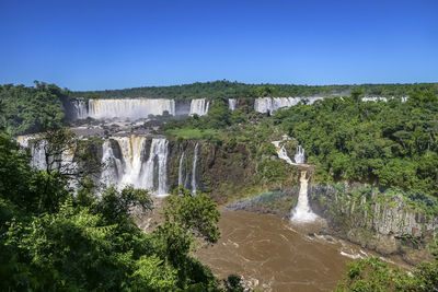 Scenic view of waterfall against clear blue sky