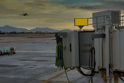 Airplane flying over airport runway against sky during sunset