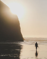 Silhouette man on beach against sky during sunset