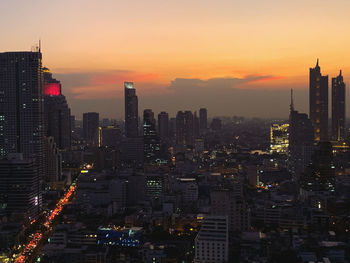 Illuminated cityscape against sky during sunset