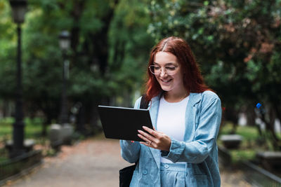 Businesswoman wearing blue suit talking on tablet with business partners while smiling. flare light