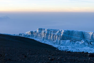 Scenic view of snow covered land against sky during sunset