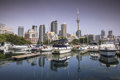 Sailboats moored in city by buildings against clear sky