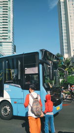 Rear view of people on street in city against sky