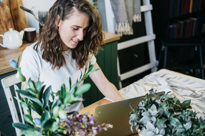 Beautiful woman in the kitchen working on a laptop.