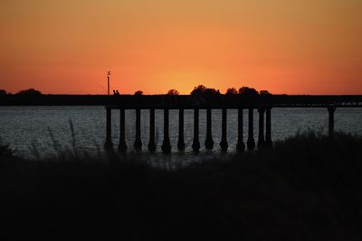 Silhouette pier over sea against sky during sunset