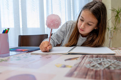 Girl writing homework on table at home