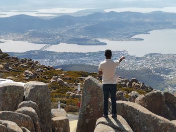 Rear view of man standing on rock look out of hobart city