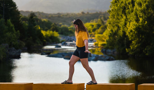 Woman standing by lake against trees