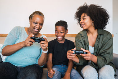 Happy family playing video game while sitting on sofa at home