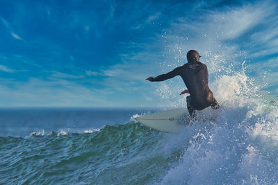 Full length of man surfing in sea against sky