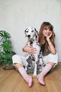 Portrait of woman with dog sitting on wooden floor